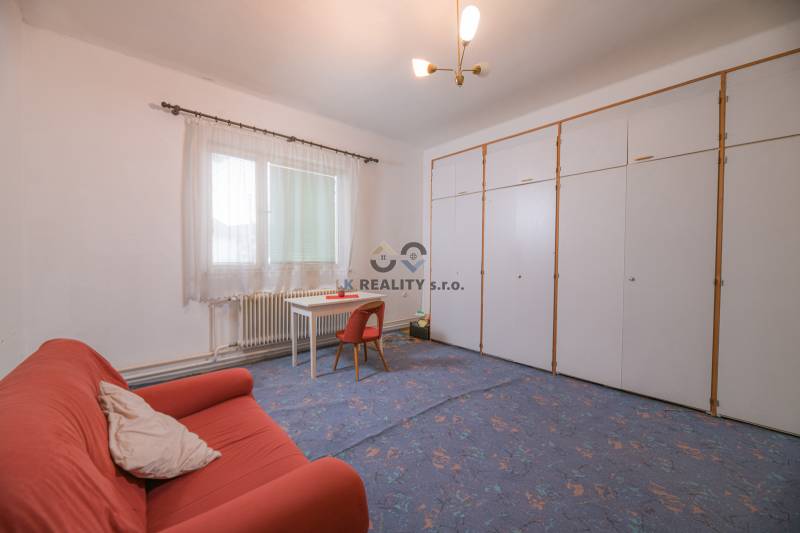 Das Einfamilienhaus enthält ein Wohnzimmer mit Teppichboden, ein oranges Sofa und einen weißen Tisch.