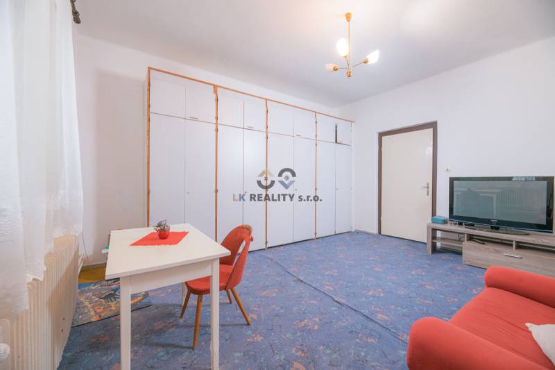 Wohnzimmer in einem Einfamilienhaus mit blauem Teppich, ausziehbarem Sofa und Aufbewahrungsschränken.