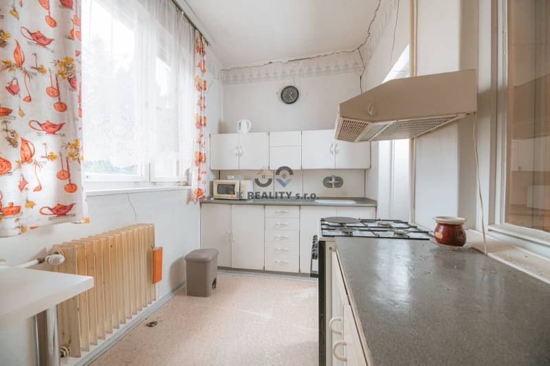 Eine Küche in einem Einfamilienhaus mit weißen Schränken, einem Herd und bunten Vorhängen.