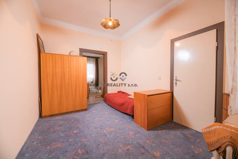 Ein Zimmer in einem Einfamilienhaus mit blauem Teppich, Holzmöbeln und einem Bett.