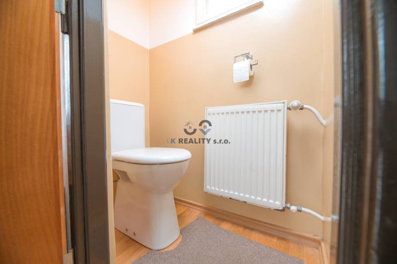 Toilette in einem Einfamilienhaus mit Heizkörper und Boden in Holzoptik.
