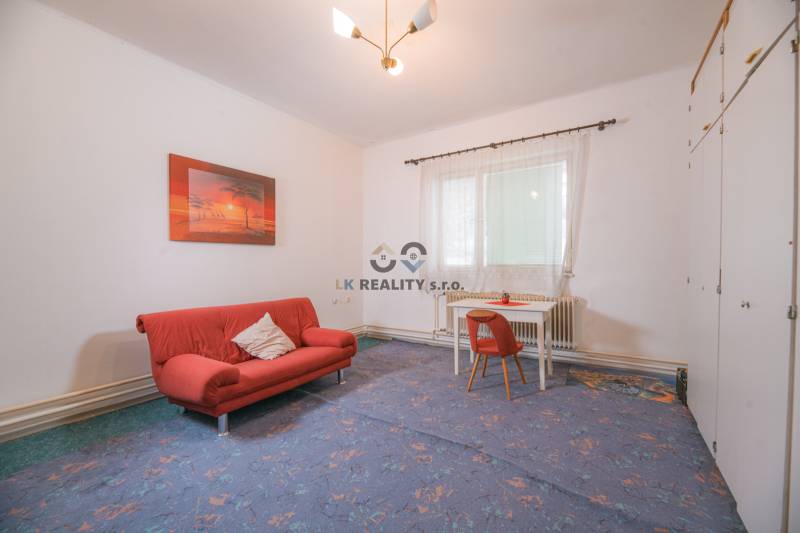 Wohnzimmer in einem Einfamilienhaus mit rotem Sofa und Tisch mit Stuhl.