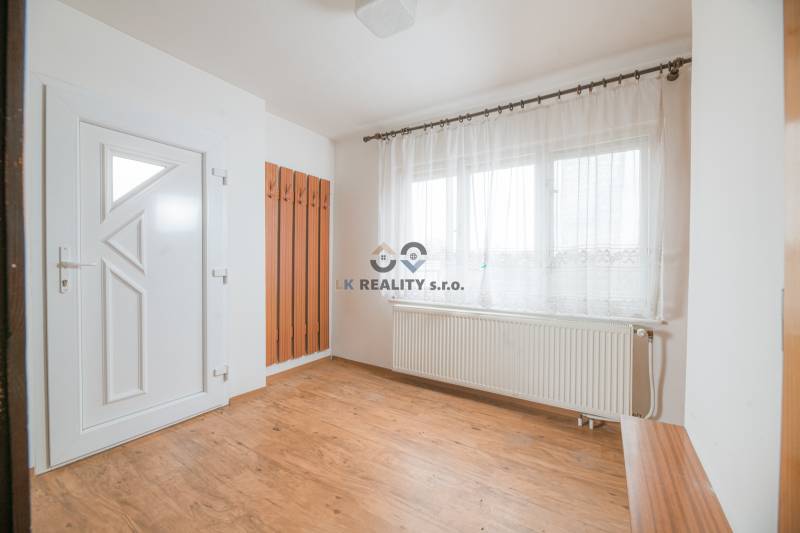 Innenraum eines Einfamilienhauses mit weißen Wänden, Fenstern und einem Boden in Holzoptik.