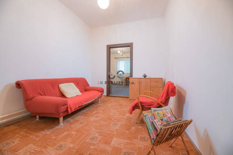 Wohnzimmer mit rotem Sofa, Sessel, Zeitschriften und Holzboden in einem Einfamilienhaus.