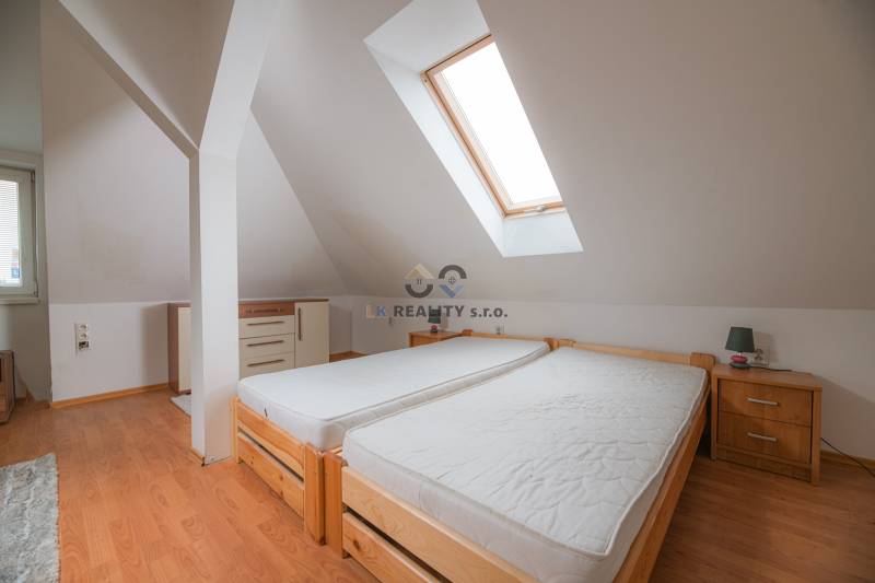 Dachbodenschlafzimmer mit zwei Einzelbetten und Holzboden in einer Zweizimmerwohnung.