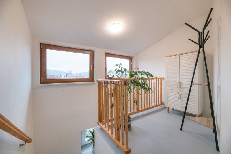 Fenster mit Holzrahmen, Geländer, Pflanze, weiße Möbel in einer 2-Zimmer-Wohnung.