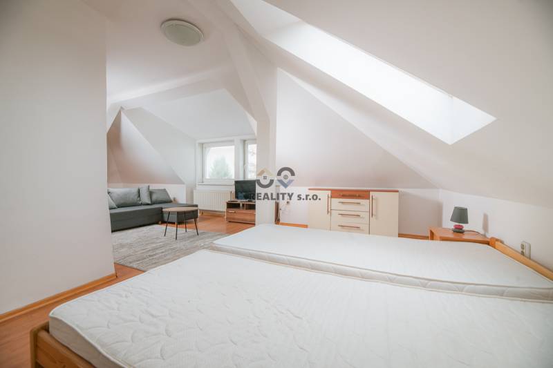 Innenraum einer 2-Zimmer-Wohnung mit Bett, Sofa und Boden in Holzoptik.