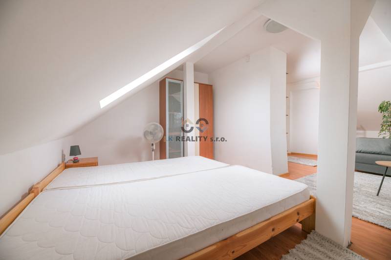 Dachbodenschlafzimmer in einer 2-Zimmer-Wohnung mit Bett und Schrank, Teppichboden.