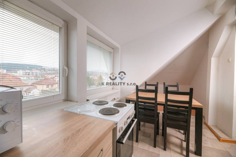 Küche in einer 2-Zimmer-Wohnung mit Herd, Mikrowelle und Esstisch, mit Blick auf die Stadt.