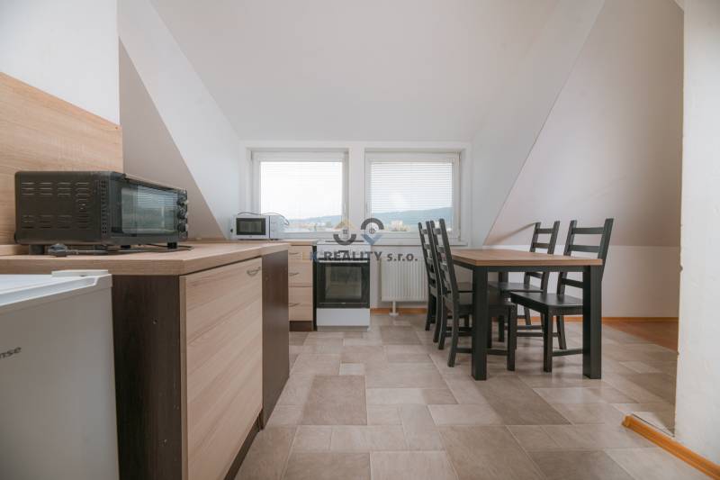 Küche in einer 2-Zimmer-Wohnung mit Esstisch, Geräten und Fliesen.