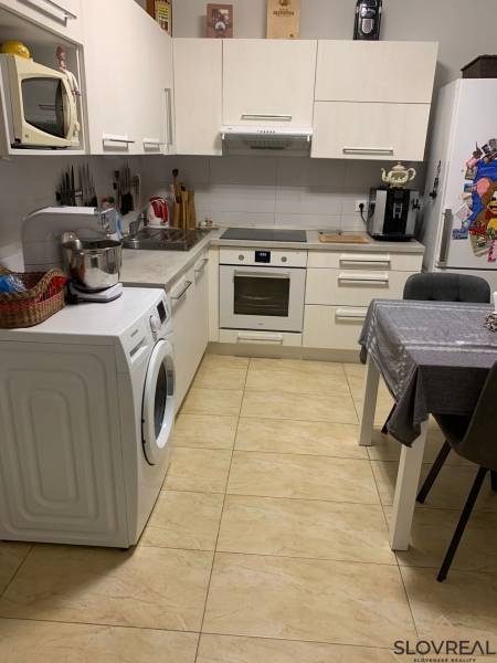 Küche in einer 2-Zimmer-Wohnung mit weißen Schränken und Keramikboden.