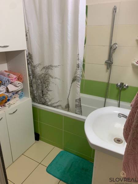 Badezimmer mit Badewanne und bunten Fliesen in einer 2-Zimmer-Wohnung.