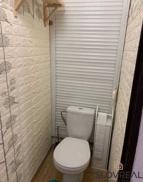 Toilette mit Schiebetüren und dekorativer Wand in einer 2-Zimmer-Wohnung.
