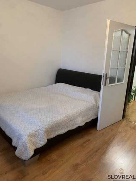 Schlafzimmer in einer 2-Zimmer-Wohnung mit Holzboden und einem großen Bett.