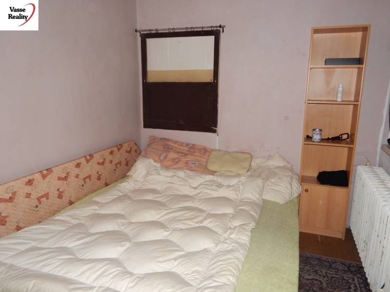 Zimmer mit Bett, Regal und Heizkörper, geeignet für Gastronomiebereiche zur Renovierung.