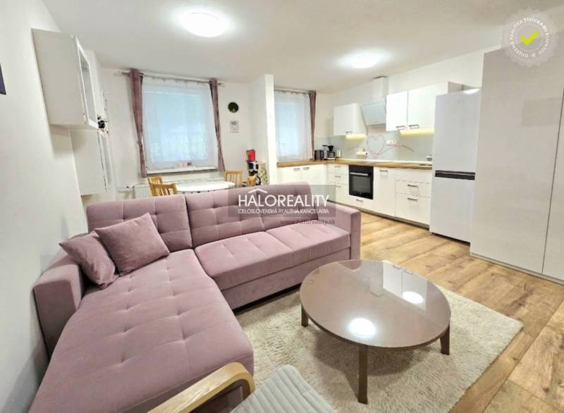 Das Wohnzimmer mit Küche in der 3-Zimmer-Wohnung verbindet ein bequemes Sofa und eine Küchenzeile.