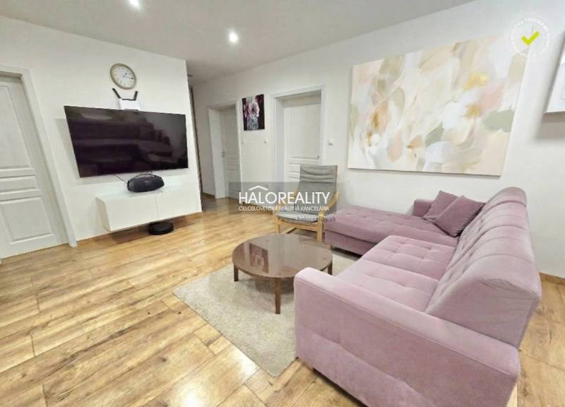 Wohnzimmer mit Holzboden und rosa Sofa in einer 3-Zimmer-Wohnung.