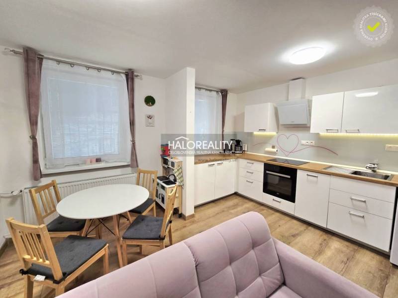 Küche in einer 3-Zimmer-Wohnung mit weißen Schränken, Boden in Holzoptik und kleinem Tisch.