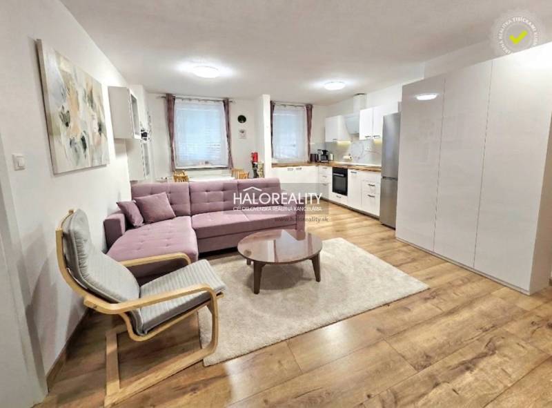 Wohnzimmer in einer 3-Zimmer-Wohnung mit Holzboden, Sofa und Küche.