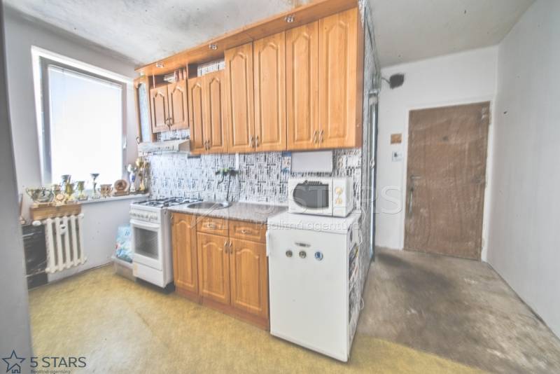 Küche mit Holzschränken und Geräten in einer Einzimmerwohnung.