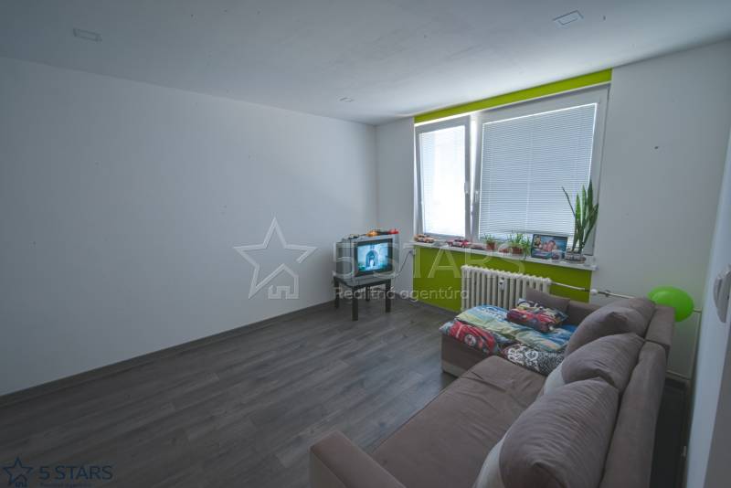 Wohnzimmer in einer Einzimmerwohnung mit Holzboden und hellen Wänden.