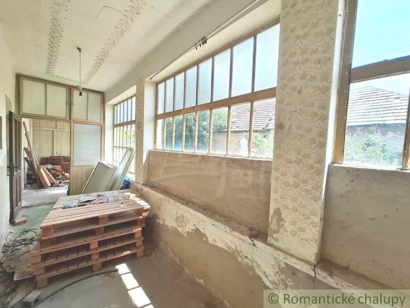 Eine Hütte mit einer geräumigen Veranda, großen Fenstern und vielfältigem gelagertem Material.