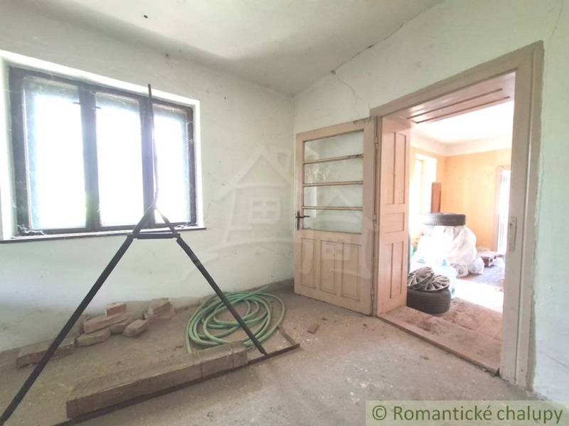 Ein Raum in einer Hütte mit Licht aus dem Fenster, offenen Türen und Baustellenunordnung.
