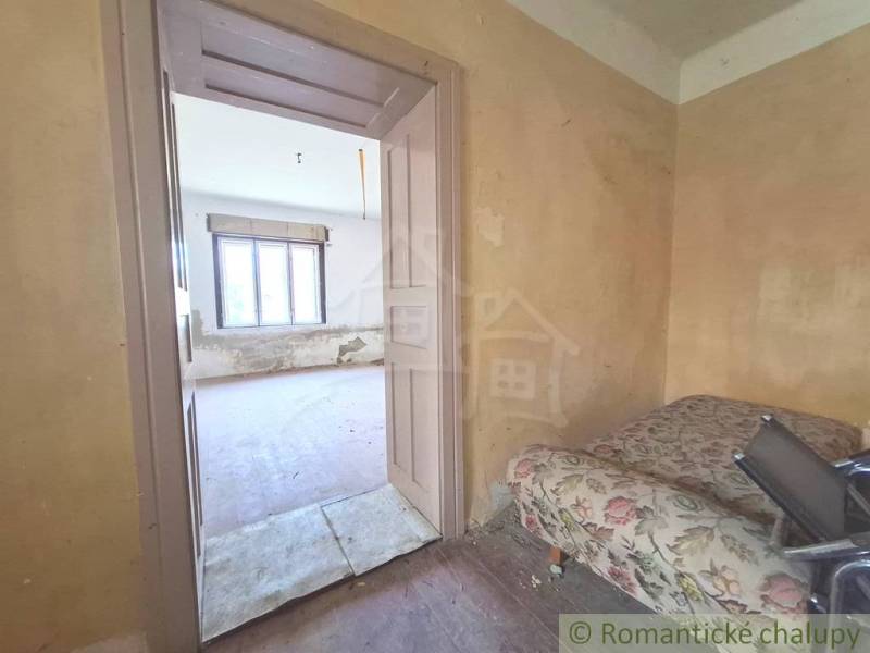 Ein Zimmer in einer Hütte mit alten Möbeln und einem Fenster wartet auf die Renovierung.