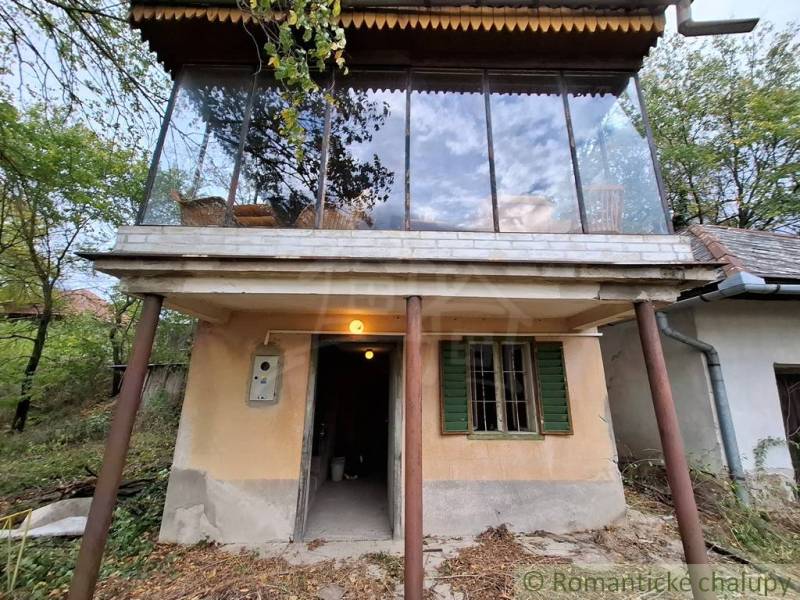 Ein Ferienhaus in Kamenín mit einer verglasten Terrasse, umgeben von Natur und Bäumen.
