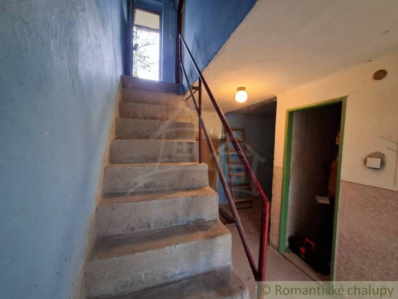 Betontreppen im Inneren der Hütte mit blauen Wänden und einem Metallgeländer.