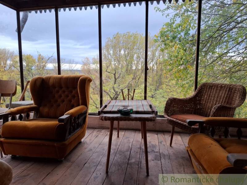 Eine Hütte mit Sitzgelegenheiten aus antiken Sesseln und Blick auf den Herbstwald.