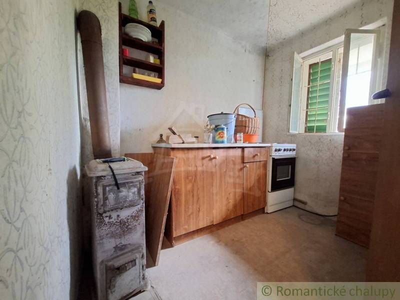 Das Innere der Hütte mit einer einfachen Küchenzeile, einem Ofen und einem offenen Fenster.