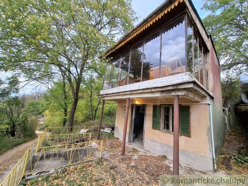 Ein Ferienhaus in Kamenín, umgeben von Grün, mit einer verglasten Terrasse und einer Zufahrtsstraße.