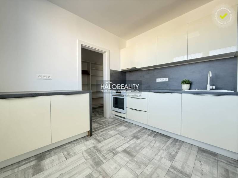 Küche in einer 2-Zimmer-Wohnung mit grauem Boden in Holzoptik und weißen Schränken.