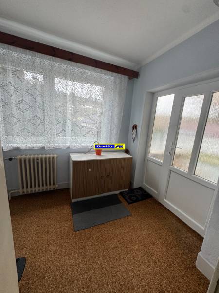 Innenraum eines Einfamilienhauses mit Teppich, Heizkörper und Schrank unter dem Fenster.