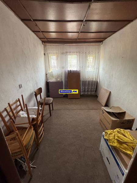 Einfaches Zimmer mit Kartons und Holzstühlen in einem Einfamilienhaus.