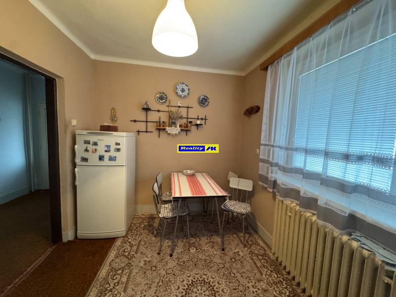 Küche in einem Einfamilienhaus mit Kühlschrank, Tisch und Dekorationsgegenständen an der Wand.