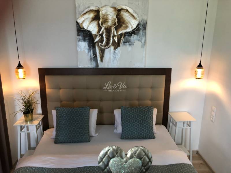 Schlafzimmer mit stilvoller Beleuchtung und einem Bild eines Elefanten in einer 2-Zimmer-Wohnung.