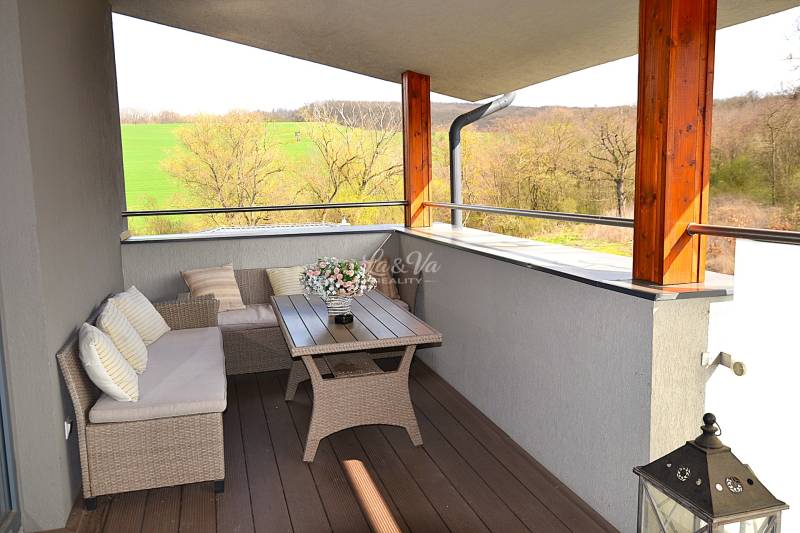 Geräumiger Balkon mit Rattanmöbeln und Boden in Holzoptik in einem Einzimmerapartment.