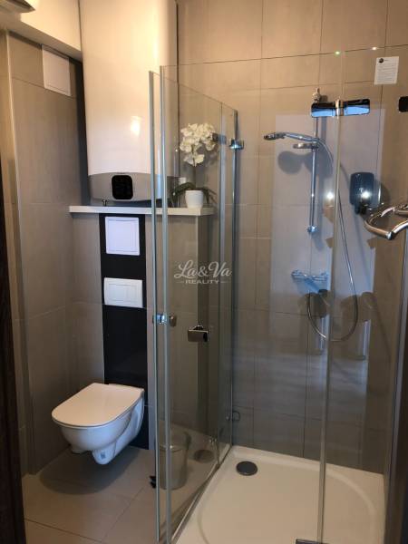 Badezimmer in einer 2-Zimmer-Wohnung mit Duschkabine und Toilette, elegante Dekoration.