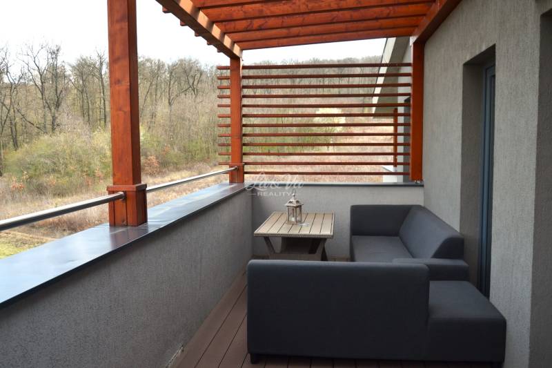 Balkon einer 2-Zimmer-Wohnung mit Holzdekor und Blick ins Grüne.