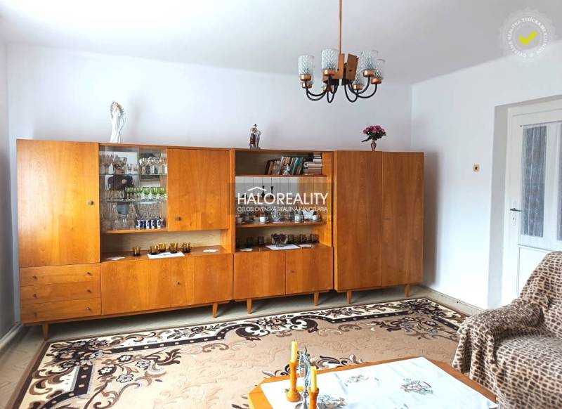 Wohnzimmer in einem Einfamilienhaus mit einer Wohnwand aus Holz und einem Kronleuchter.