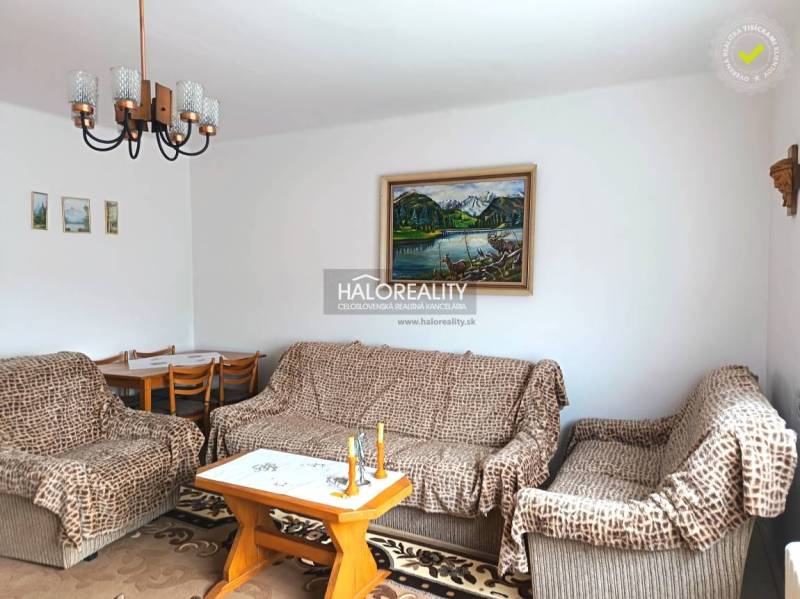 Obývacia izba rodinného domu s pohovkou, obrazom a jedálenským stolom.