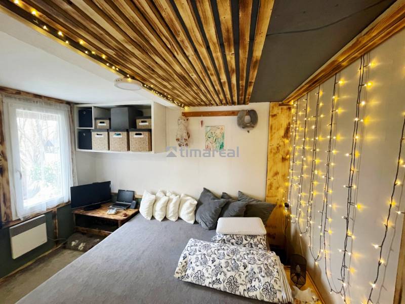 Innenraum eines Einfamilienhauses mit Lichterketten, Holzboden und einem bequemen Bett.