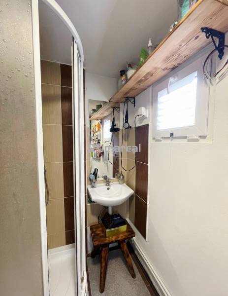 Kompaktes Badezimmer mit Holzregal und Duschkabine in einem Einfamilienhaus.