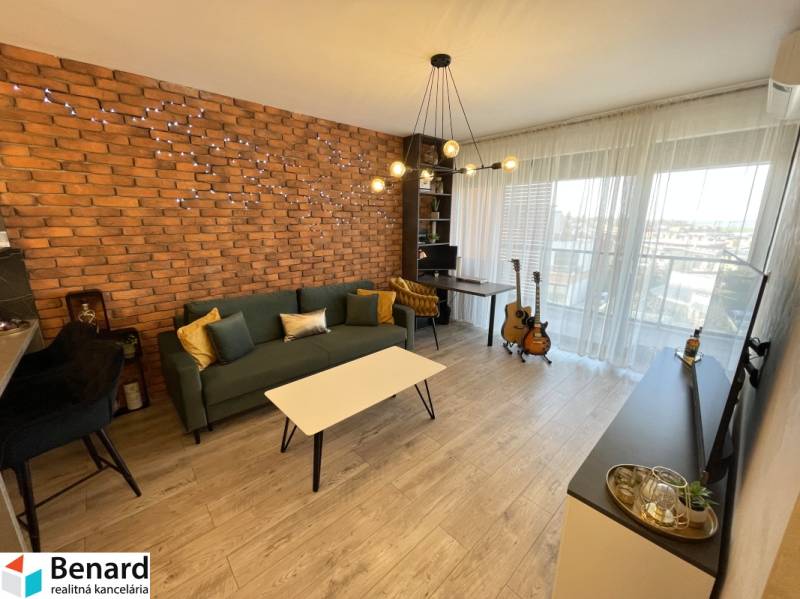 Wohnzimmer in einer 2-Zimmer-Wohnung mit Ziegelverkleidung und Holzboden.