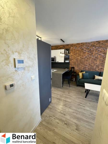 Innenraum einer 2-Zimmer-Wohnung mit Holzboden, Ziegelwand und Küchenzeile.