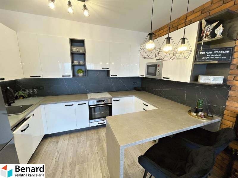 Küche in einer 2-Zimmer-Wohnung mit weißen Schränken und einem Boden in Holzoptik.