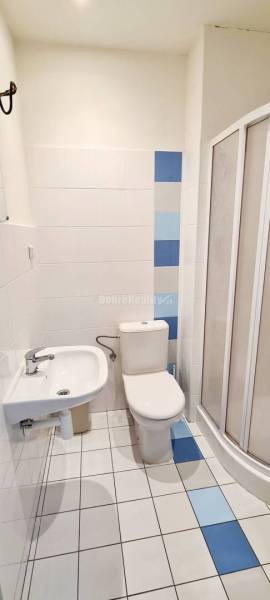 Badezimmer im Büro mit Keramikfliesen, Duschkabine und weißen Fliesen.