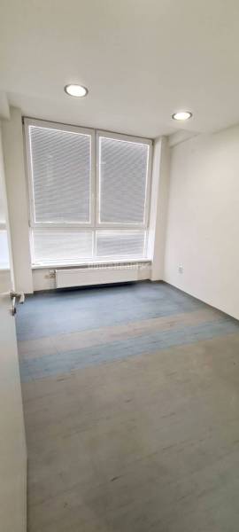 Ein Raum mit großen Fenstern, einem Holzdekorboden und einem Heizkörper im Büro.